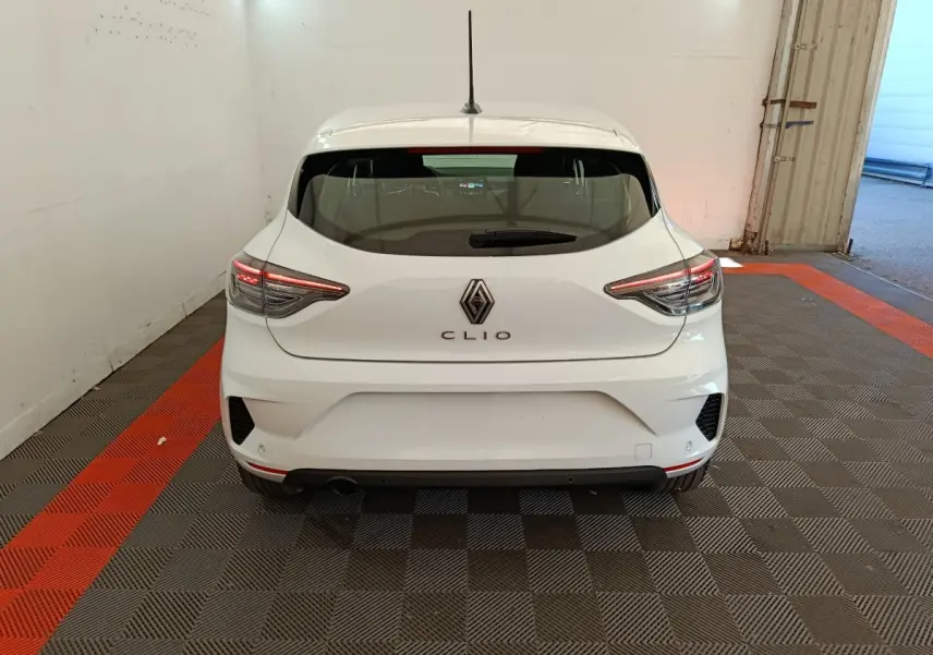 Vue arrière d'une Renault Clio blanche 2024 avec feux LED et logo Renault centré sur un sol à damier gris et rouge.