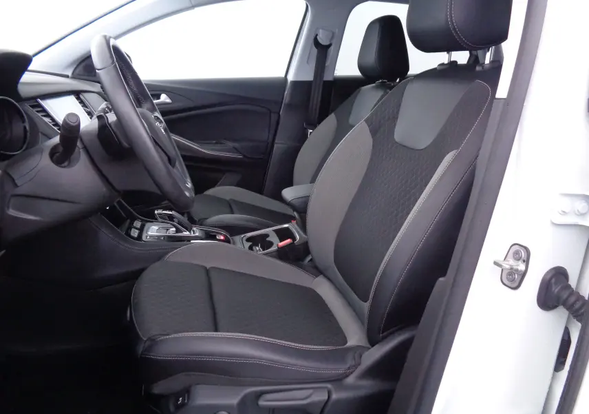 Vue intérieure côté conducteur de l'Opel Grandland X blanc métal, sièges tissu noir et gris avec coutures apparentes.