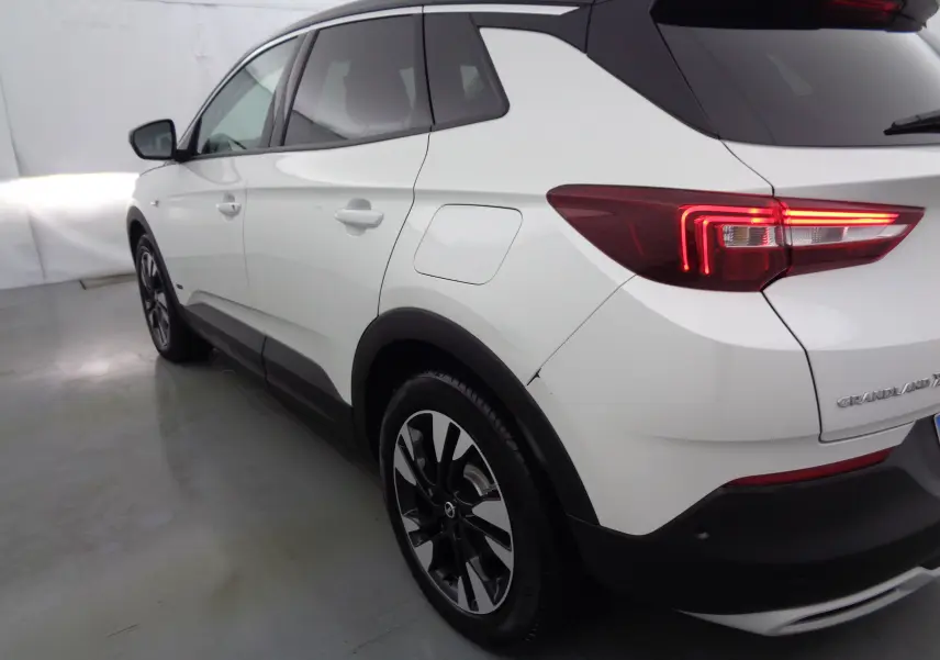 Vue 3/4 arrière droite d'un Opel Grandland X blanc métal avec feux arrière LED et jantes bicolores.
