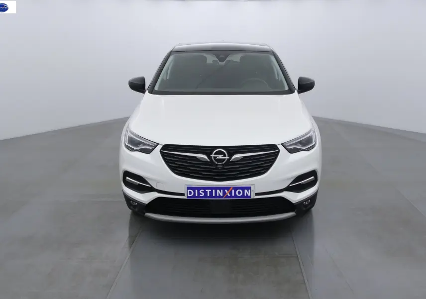 Vue frontale d'un Opel Grandland X blanc métal avec calandre noire et phares LED allumés.