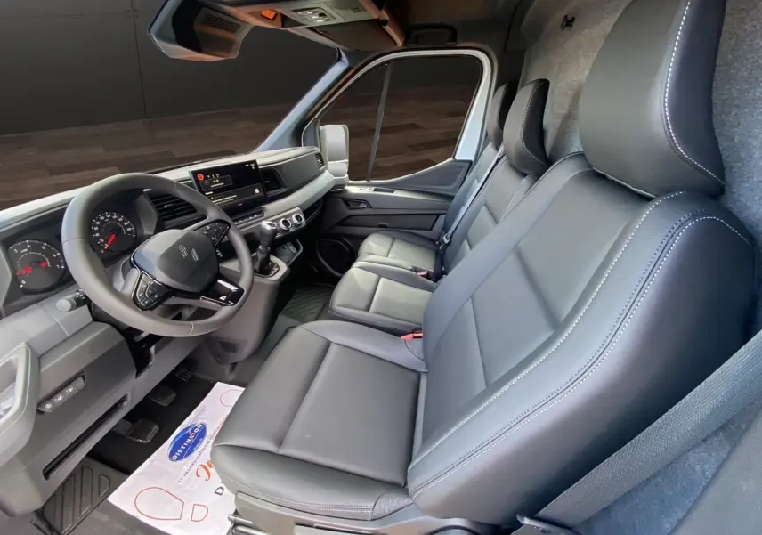 Intérieur du Renault Master 2025 vu côté droit, sièges gris foncé en cuir et tableau de bord moderne avec écran tactile.