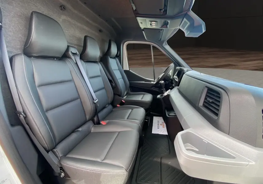 Vue intérieure côté passager du Renault Master 2025 avec banquette 3 places en cuir noir et tableau de bord gris.