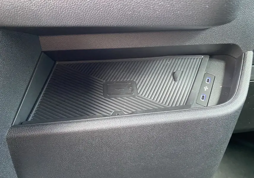Gros plan sur le chargeur sans fil et les ports USB intégrés dans la console intérieure noire du Renault Master blanc.