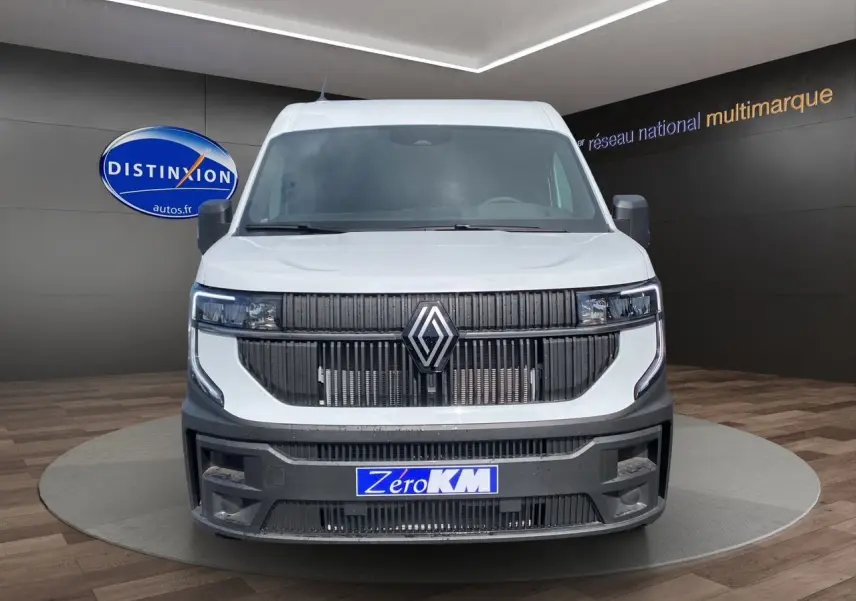 Vue frontale d'un Renault Master blanc avec calandre noire et plaque "Zéro KM" en showroom.