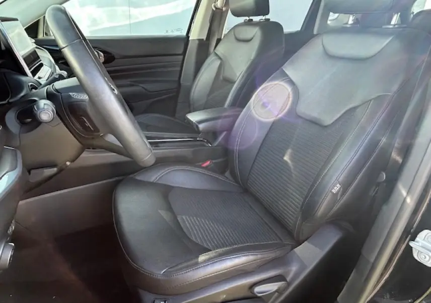 Vue intérieure côté conducteur du Jeep Compass noir 2021, sièges en cuir mixte TEP/tissu avec accoudoir central.