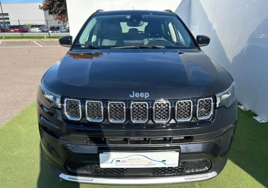 Vue avant d'un Jeep Compass noir métallisé avec calandre chromée et feux LED, stationné sur un tapis vert.