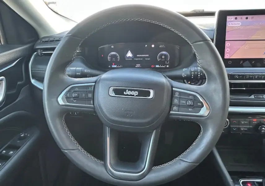 Vue intérieure centrée sur le volant cuir noir du Jeep Compass 2021 avec tableau de bord numérique et écran tactile.