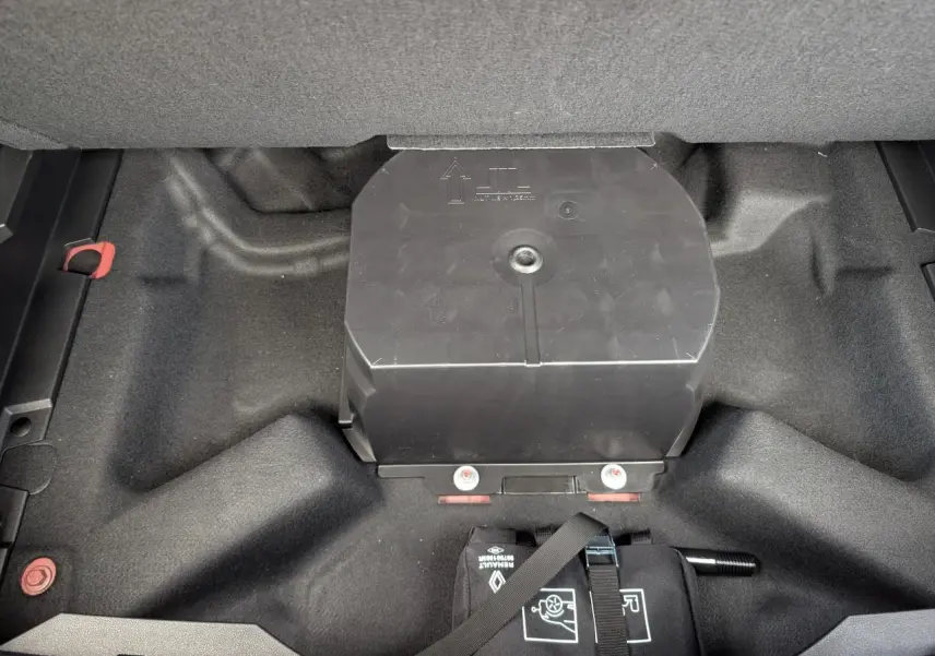 Compartiment de rangement noir dans le coffre du Renault Austral 2025, vue plongeante sur l'espace sous le plancher.