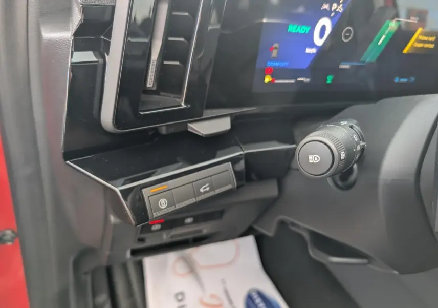 Détail de la planche de bord côté gauche du Renault Austral rouge, avec commandes et écran numérique allumé.