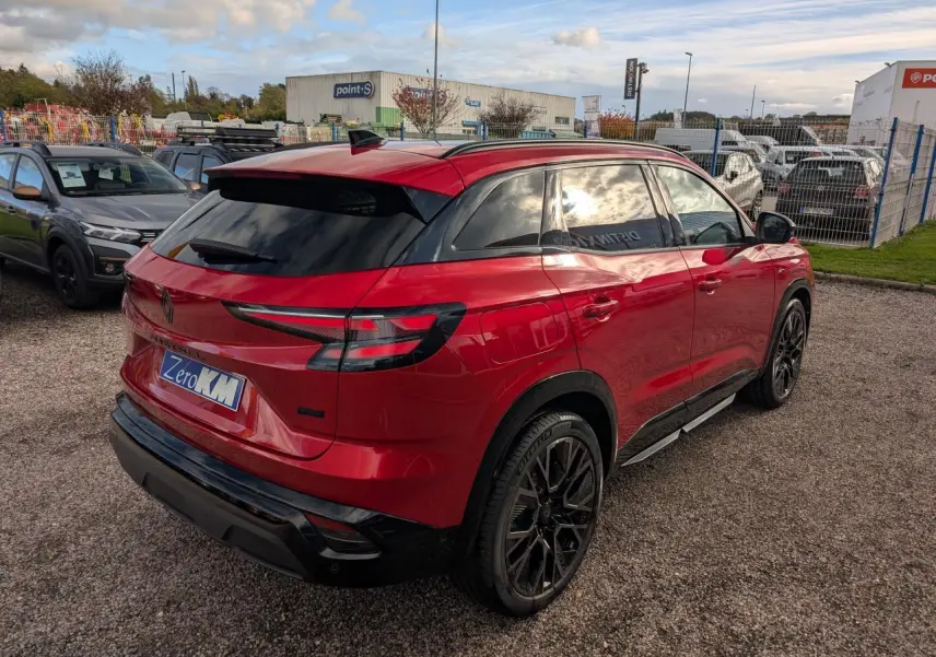 Vue 3/4 arrière droite d'un Renault Austral rouge métallisé avec jantes noires et vitres teintées.