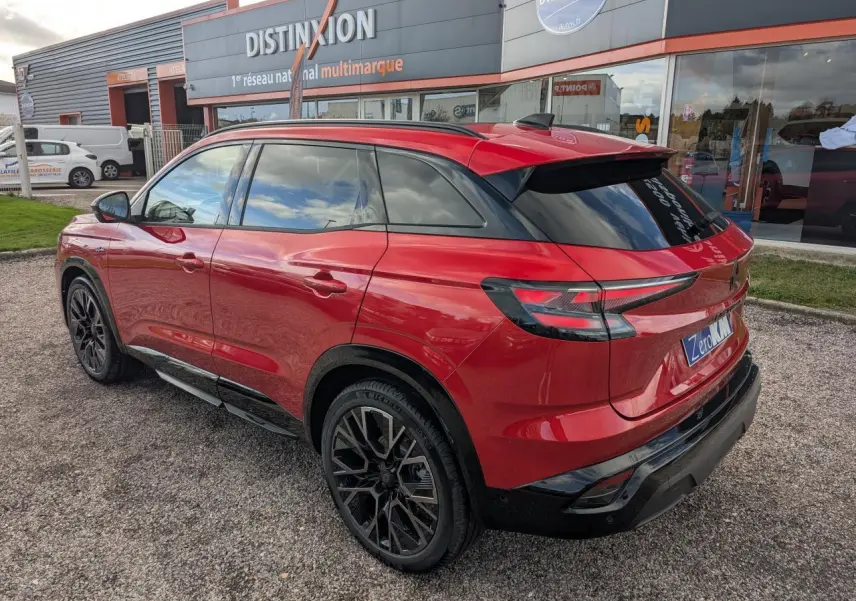 Vue 3/4 arrière droite du Renault Austral rouge métallisé avec jantes noires et toit panoramique fixe.