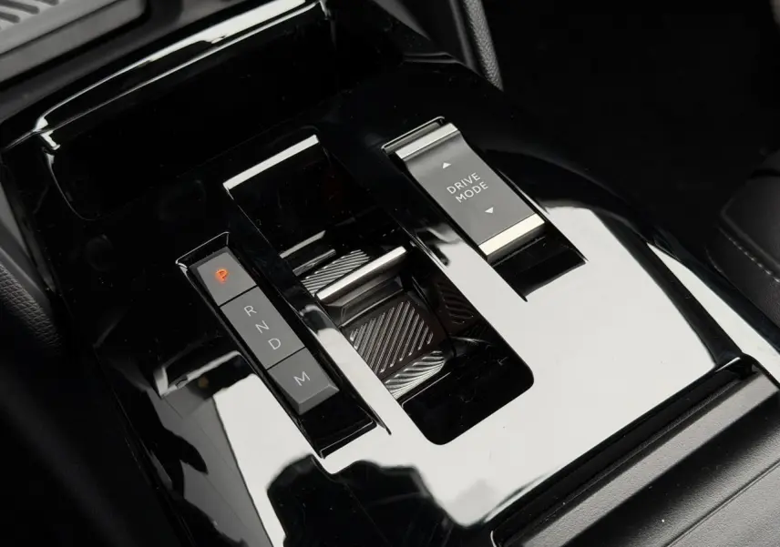 Gros plan sur la console centrale noire brillante du Citroën C4 2025, avec commandes de boîte auto et mode de conduite.