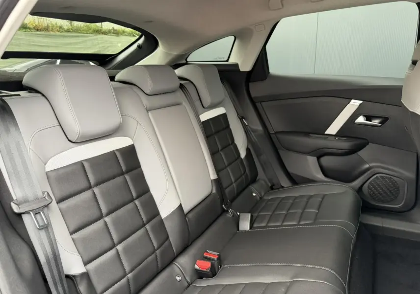 Vue latérale droite des sièges arrière bicolores gris clair et noir de la Citroën C4 NV Hybrid 2025 avec finitions en tissu et cuir.
