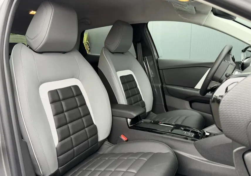 Vue intérieure côté gauche des sièges avant gris clair et noir de la Citroën C4 NV Hybrid 2025 avec accoudoir central.