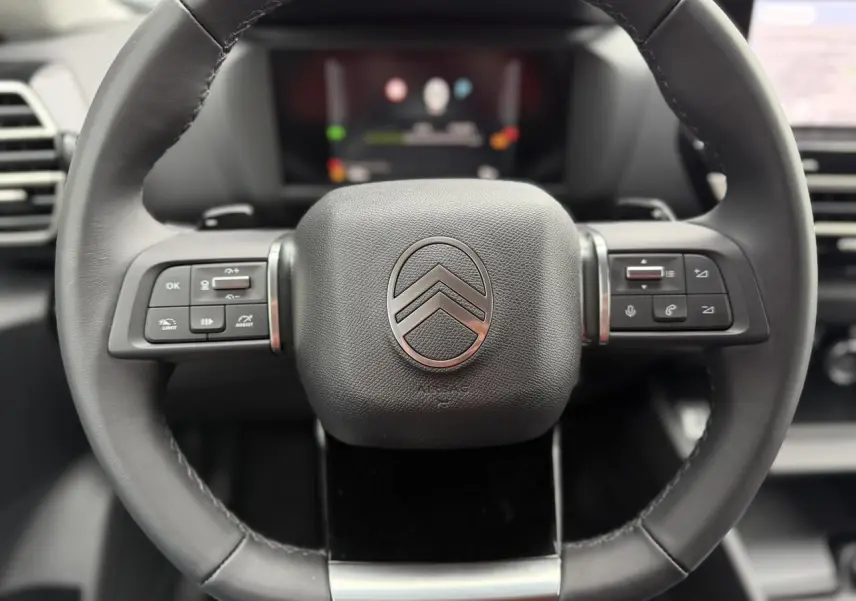 Volant cuir noir de Citroën C4 2025 avec commandes intégrées et logo double chevron au centre.
