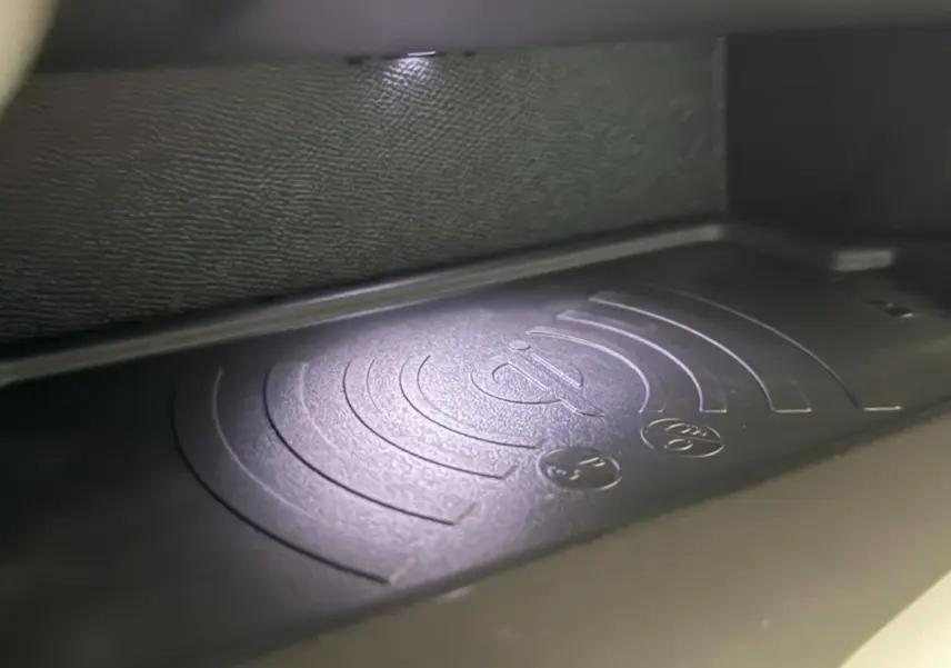 Gros plan sur le chargeur sans fil intégré dans l'habitacle de la Peugeot 308 rouge 2025.