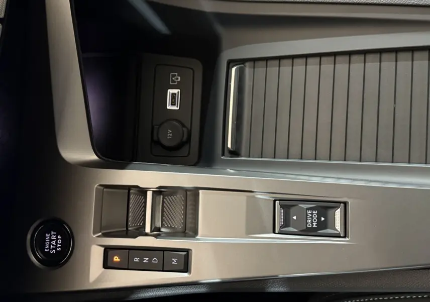 Gros plan sur la console centrale grise de la Peugeot 308 rouge, avec levier de vitesses automatique et bouton Drive Mode.