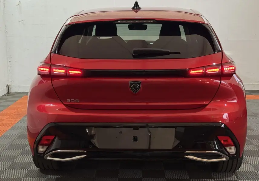Vue arrière d'une Peugeot 308 rouge 2025 avec feux LED allumés et double sortie d'échappement chromée.