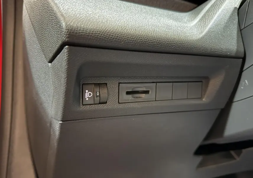 Détail du tableau de bord côté gauche de la Peugeot 308 rouge 2025, avec commande réglage hauteur des phares.