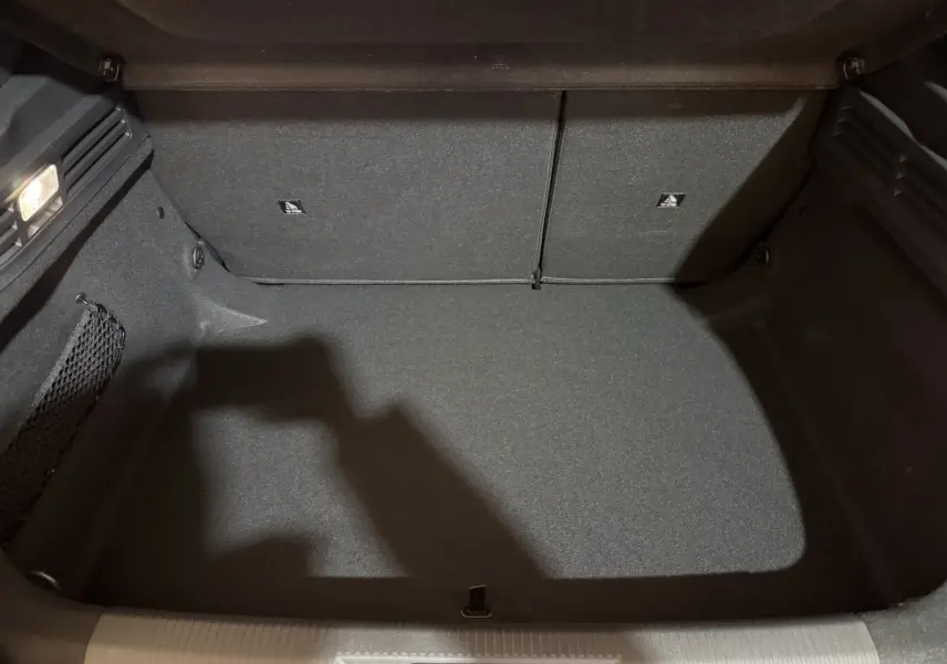 Coffre vide vu de face du Peugeot 308 2025, revêtement intérieur gris foncé avec filet de rangement latéral.