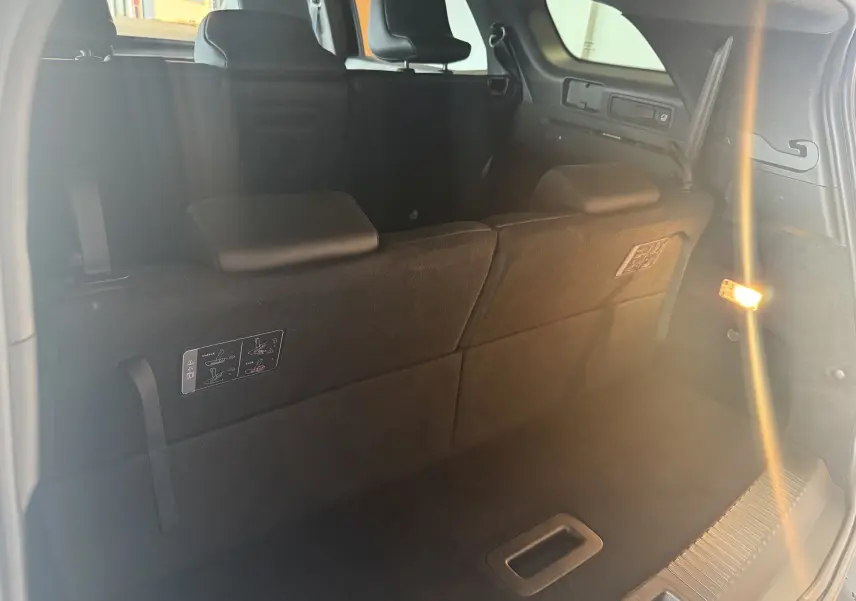 Vue intérieure du coffre arrière du Renault Espace VI E-Tech 200 Esprit Alpine noir, sièges rabattus et éclairage latéral allumé.