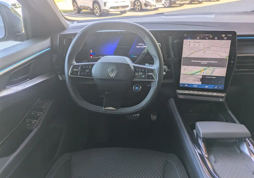 Vue intérieure frontale du tableau de bord du Renault Espace VI hybride, avec volant multifonction et écran tactile vertical.