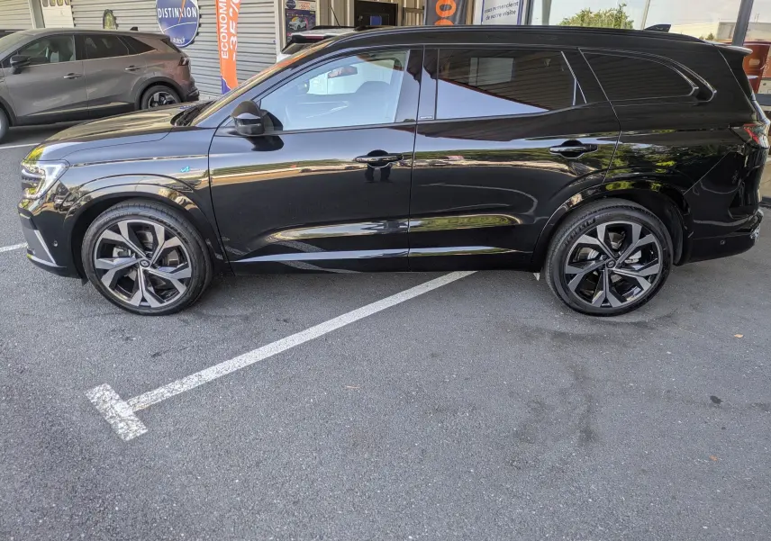 Profil côté gauche du Renault Espace VI E-Tech Full Hybrid noir étoile avec jantes alliage 20 pouces Daytona et vitres teintées.