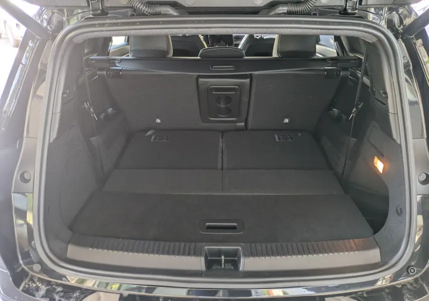 Coffre ouvert vu de l'arrière du Renault Espace VI noir Étoile avec banquette arrière rabattue et espace de chargement plat.