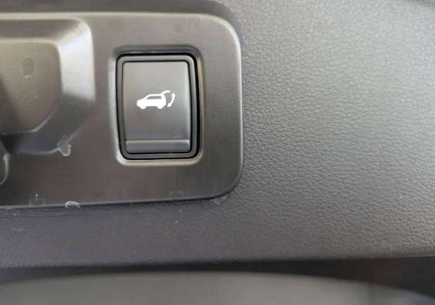 Gros plan sur le bouton d'ouverture électrique du hayon dans l'habitacle du Renault Espace VI noir étoile.