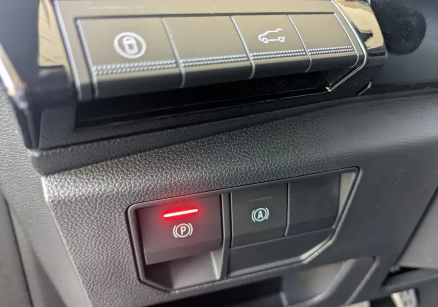 Gros plan sur les commandes de frein à main électronique et arrêt automatique du moteur du Renault Espace VI noir étoile.