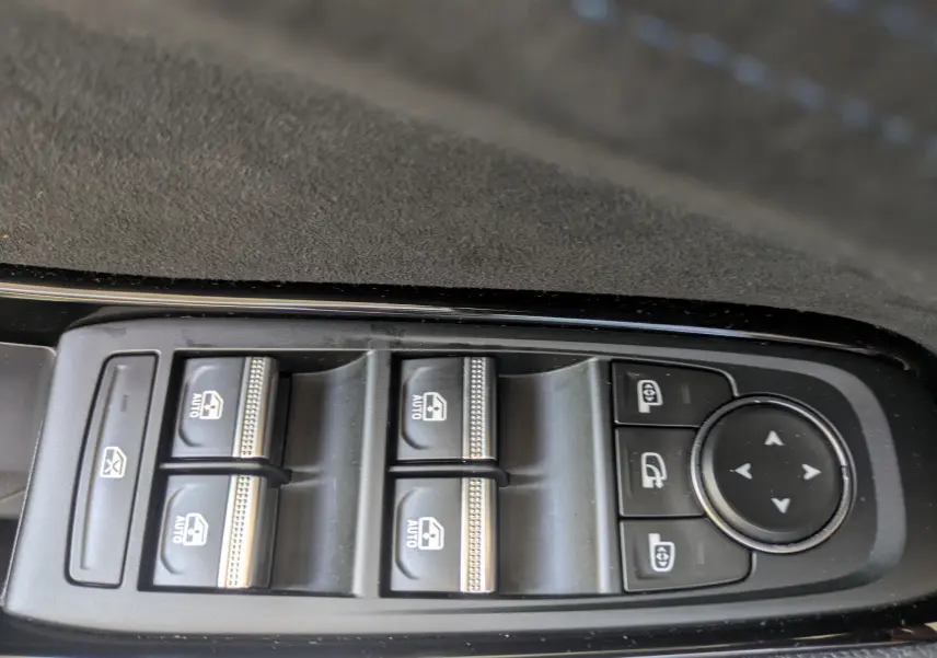 Gros plan sur les commandes de lève-vitres et rétroviseurs du côté gauche intérieur du Renault Espace VI noir étoile.