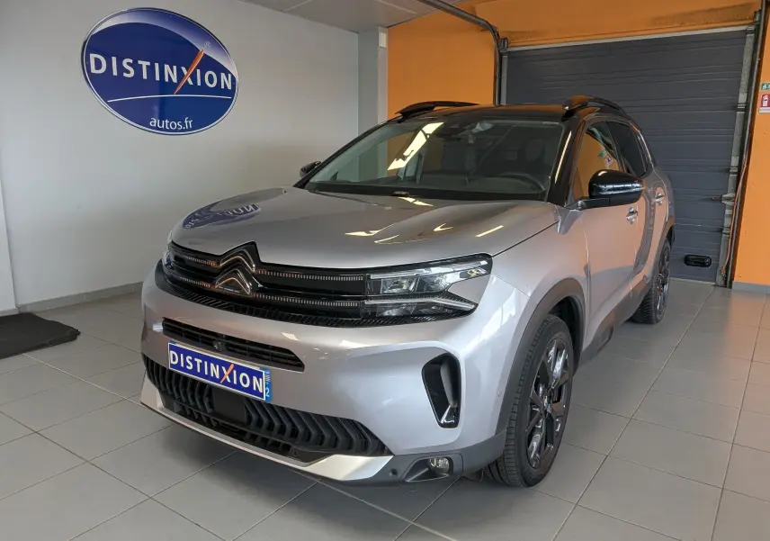 Vue 3/4 avant droite d'un Citroën C5 Aircross gris Artens avec toit noir, en intérieur showroom.