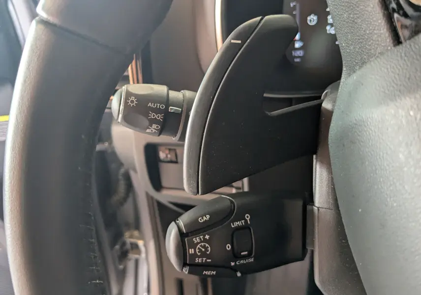 Gros plan sur la commande de régulateur de vitesse et palettes au volant du Citroën C5 Aircross gris Artens 2024.