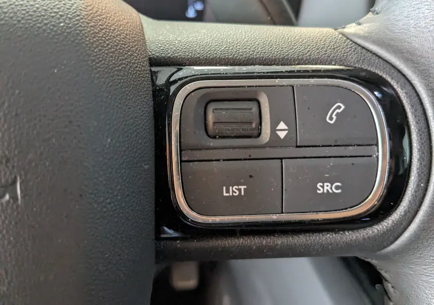 Gros plan sur les commandes au volant droit du Citroën C5 Aircross gris Artens 2024, boutons LIST, SRC et téléphone.
