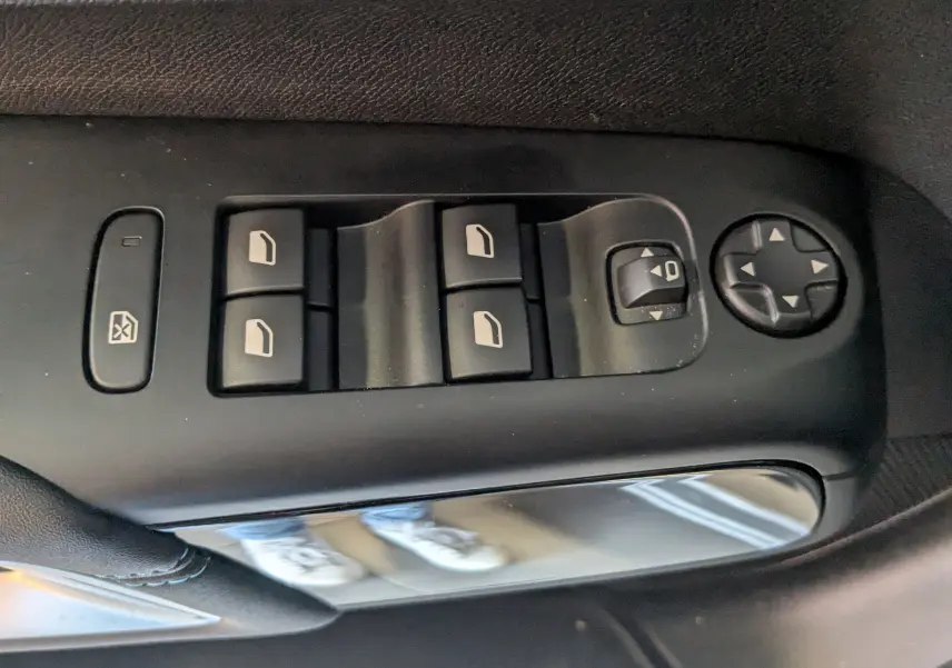 Gros plan sur les commandes de lève-vitres et réglage des rétroviseurs côté conducteur d’un Citroën C5 Aircross gris Artens.