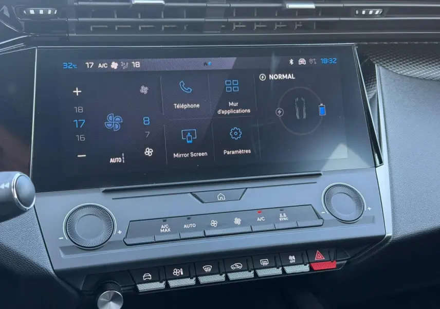 Vue rapprochée de l’écran tactile central et des commandes de climatisation de la Peugeot e-308 noire, intérieur moderne et épuré.