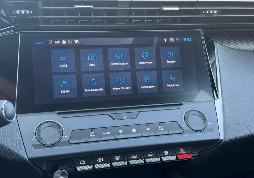 Vue rapprochée de l’écran tactile central et des commandes de climatisation de la Peugeot e-308 noire, intérieur moderne.