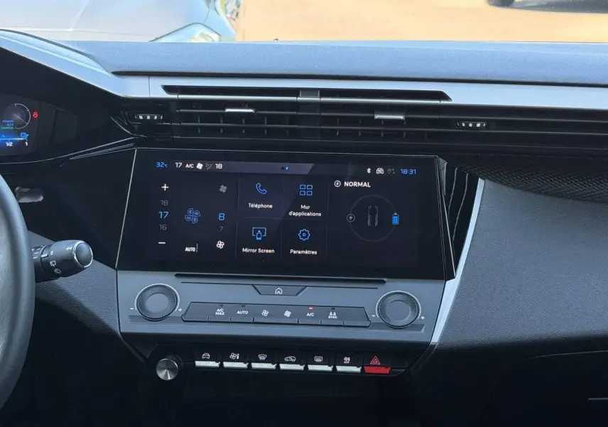 Vue intérieure centrée sur la console tactile et les commandes climatisation du Peugeot e-308 noir Perla Nera 2025.