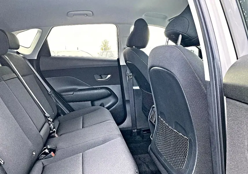 Vue intérieure côté droit sur la banquette arrière grise du Hyundai Kona 2025 avec appuie-têtes et porte arrière ouvert.