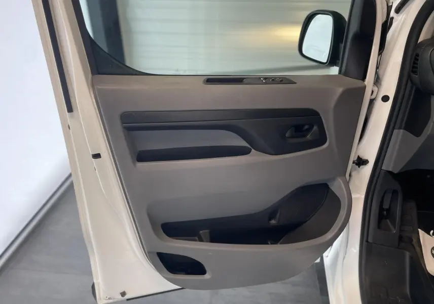 Vue en gros plan de la porte avant gauche blanche de l'Opel Vivaro avec commandes de vitres et rangement intégré.