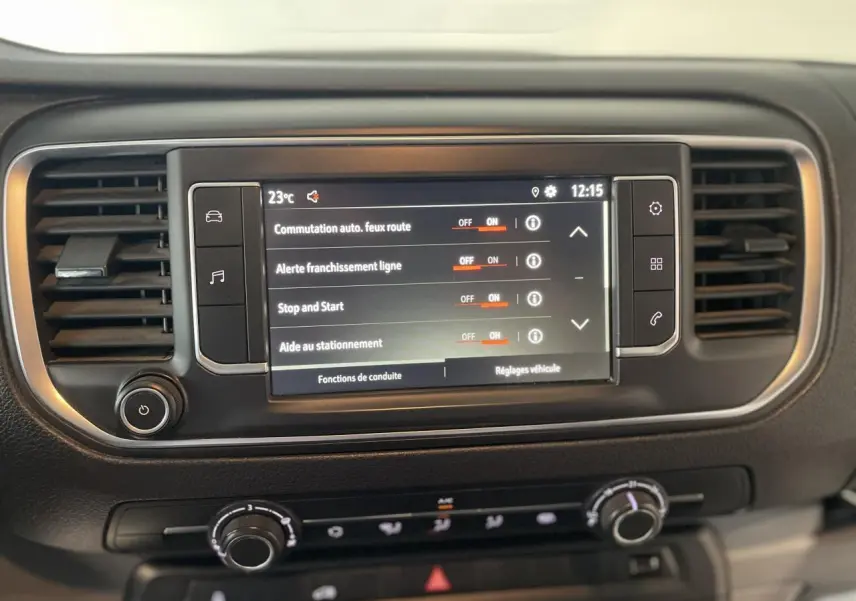 Écran tactile central du tableau de bord noir de l'Opel Vivaro blanc, affichant les réglages d'aides à la conduite.