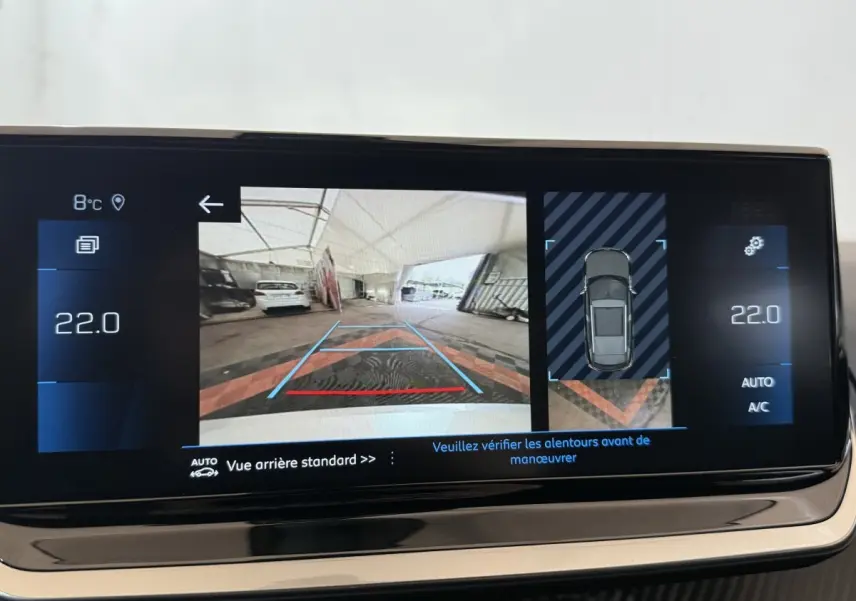 Écran tactile intérieur montrant la caméra de recul et l'aide au stationnement du Peugeot 2008 gris clair 2023.