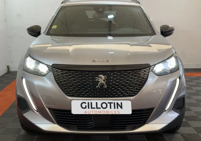 Vue avant d'une Peugeot 2008 gris clair avec phares LED allumés et calandre noire distinctive.