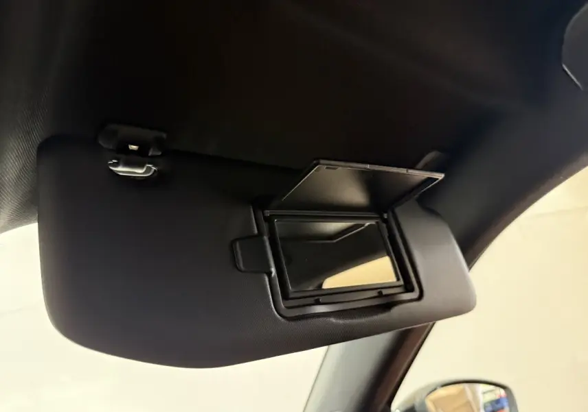 Miroir de courtoisie ouvert sur pare-soleil côté conducteur dans l’habitacle d’un Peugeot 2008 gris clair 2023.