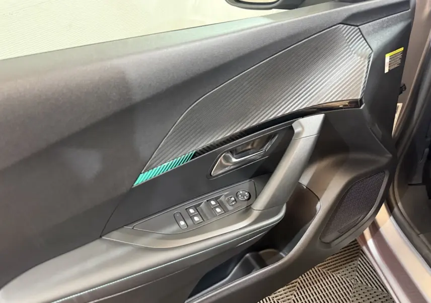 Vue rapprochée de la porte avant gauche du Peugeot 2008 gris clair, avec commandes électriques et insert décoratif.