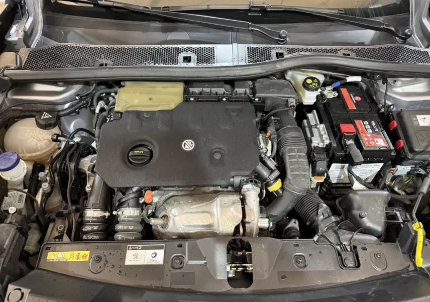 Vue plongeante sur le moteur diesel gris clair du Peugeot 2008 2023, avec batterie et composants visibles.