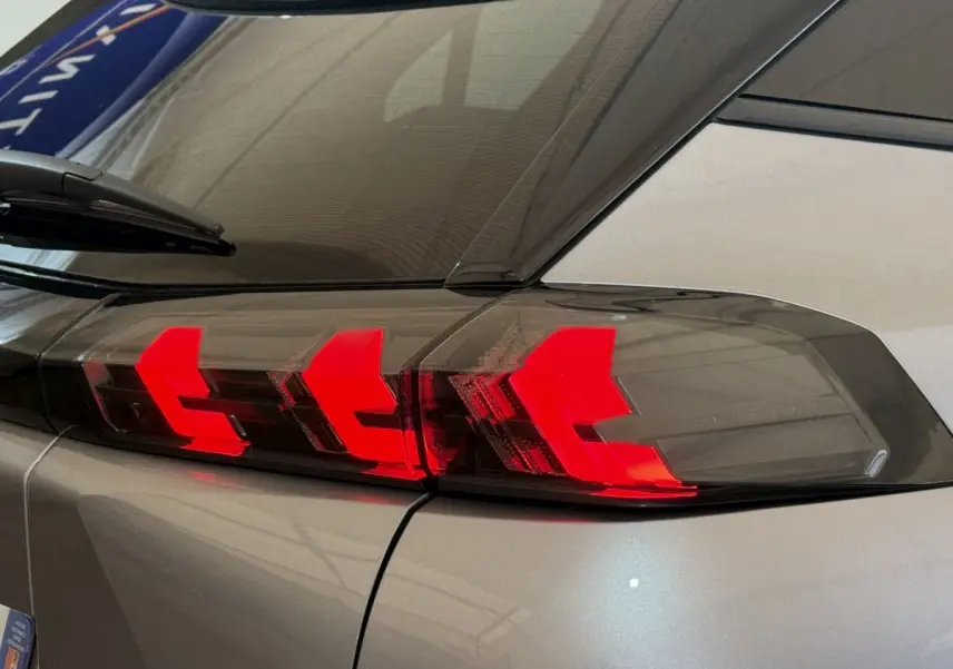 Gros plan sur le feu arrière droit rouge vif d’un Peugeot 2008 gris clair 2023, avec vitrage teinté.