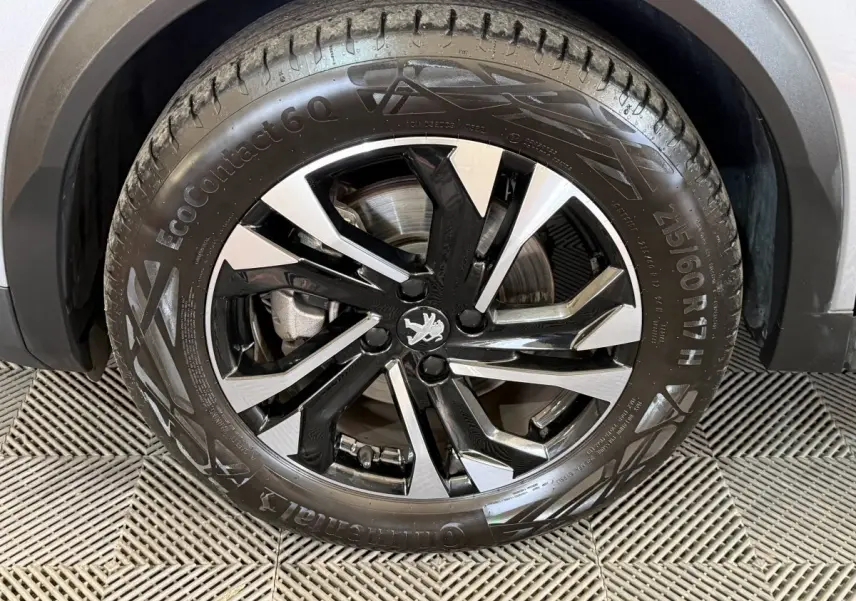 Gros plan sur la roue avant gauche du Peugeot 2008 gris clair avec jante alliage noire et argentée.