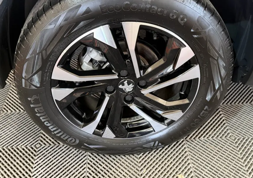 Gros plan sur la roue avant droite de la Peugeot 2008 gris clair, avec jante alliage bicolore et logo Peugeot central.