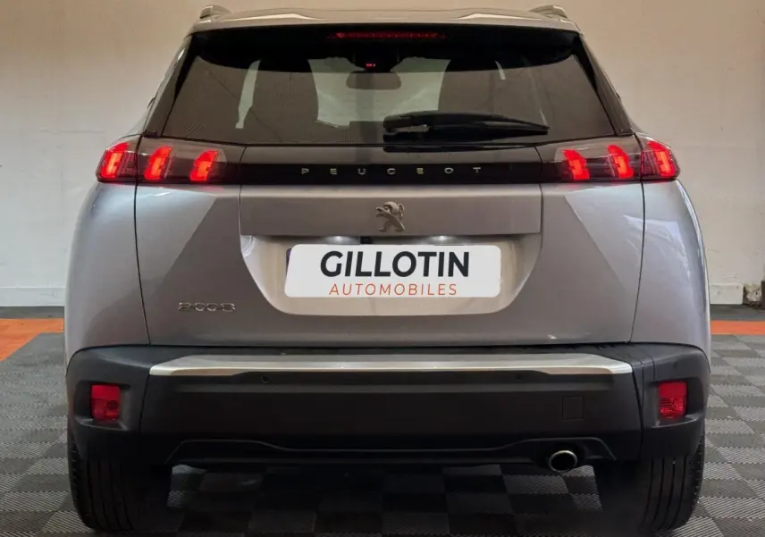 Vue arrière d'un Peugeot 2008 gris clair 2023 avec feux LED et logo lion centré sur le hayon.